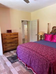 a bedroom with a purple bed and a dresser at Boston Bay, Portland Cozy Corner in Port Antonio