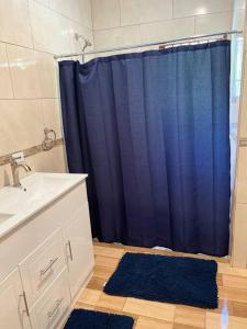 a bathroom with a blue shower curtain and a sink at Boston Bay, Portland Cozy Corner in Port Antonio