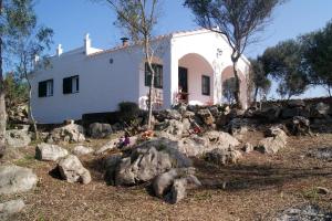 una casa blanca con rocas delante de ella en Vinya Alice, en Ciutadella