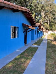 a blue building with a sidewalk in front of it at Chalé Canto da Viola in São Roque