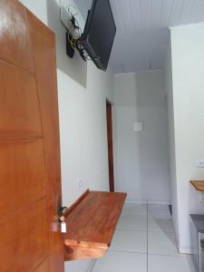 Chalé Canto da Viola في ساو روكي: غرفة مع طاولة خشبية وتلفزيون على الحائط
