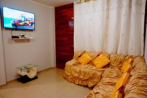 sala de estar con sofá y TV de pantalla plana en SUNRISE home, en Ica