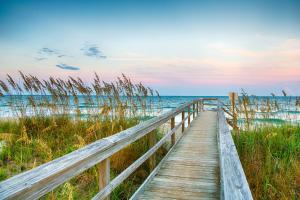 a wooden boardwalk to the beach at sunset at Battleship View in Wilmington