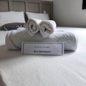 uma cama com toalhas com um cartaz em Casa temporada AURORA em São João Batista do Glória