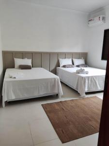 2 camas en una habitación con paredes blancas en Casa temporada AURORA, en São João Batista do Glória