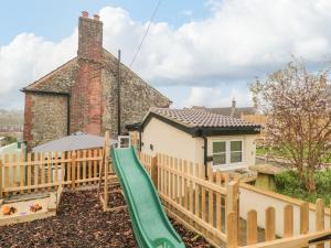 a playground with a slide in front of a house at Granary Cottage in Warminster
