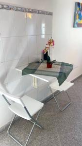 a table and two chairs and a vase with flowers at Lisbon Airport Guesthouse in Lisbon