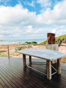 um banco de madeira sentado num deque com vista para o oceano em Wave Retreat, King Island em Loorana