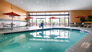 - une piscine dans un hôtel avec des tables et des chaises dans l'établissement Wyndham Minneapolis South Burnsville, à Burnsville
