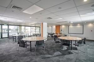 a conference room with tables and chairs and a projection screen at ibis Hamilton Tainui in Hamilton