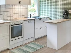 una cucina con armadi bianchi, lavandino e bancone di Holiday home Östhammar III a Östhammar