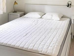 - un lit blanc avec des draps et des oreillers blancs dans l'établissement Holiday home Östhammar III, à Östhammar