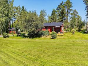 a red house in the middle of a green field at 4 person holiday home in Östhammar-By Traum in Östhammar