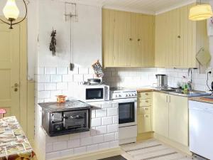 una cocina con electrodomésticos blancos y armarios amarillos en Holiday home LIDKÖPING X, en Tallbacken