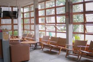 a room with a bunch of chairs and tables and windows at Augustina Home in Malang