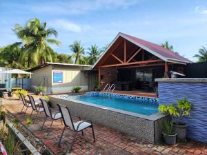 a swimming pool with chairs and a house at Homestay Umbai Kelana in Merlimau