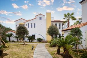 a white house with palm trees and a pathway at Hundert Hills in Jeju