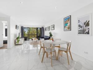a white living room with a table and chairs at Luxury Stunning Nobby's Beach Home 2bd + Den ! in Gold Coast