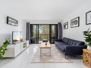 a living room with a blue couch and a tv at Luxury Stunning Nobby's Beach Home 2bd + Den ! in Gold Coast
