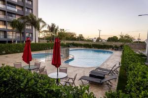 a pool with chairs and umbrellas next to a building at Livera in Santiago de los Caballeros