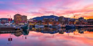 a city skyline with boats in a harbor at sunset at Little Island Apartments in Hobart