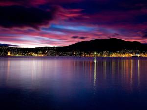 uitzicht op een meer in de nacht met een stad bij Little Island Apartments in Hobart