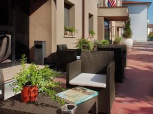 un patio avec des chaises en osier, des tables et des plantes dans l'établissement Hotel Versailles, à Colorno