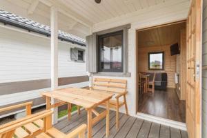 a wooden table and bench on the porch of a house at One-storey holiday houses near the beach, G ski in Gąski