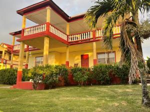 a large yellow and red house with a balcony at Sunrise Hotel in Corn Island