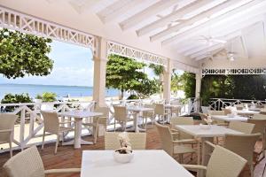 um restaurante com mesas e cadeiras brancas e o oceano em Bahia Principe Grand La Romana - All Inclusive em La Romana