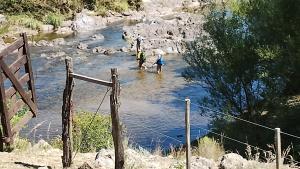 twee mensen die in het water lopen in een rivier bij La Rosadita del Paraje in Villa Yacanto
