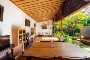 a dining room with a table and a television at Kubu Kirana by Supala in Ubud