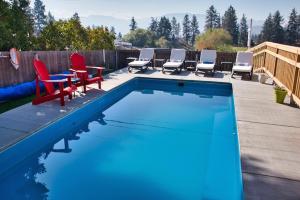 a swimming pool with chairs and a table and a group at Salish B&B and Spa in West Kelowna
