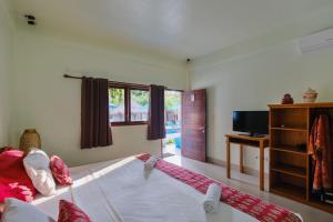 a bedroom with a bed and a tv in a room at Trawangan Nirvana in Gili Trawangan