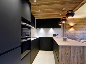 a kitchen with black cabinets and wooden ceilings at Appartement chic Méribel - skis aux pieds, cheminée & parking - FR-1-613-40 in Méribel