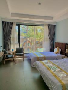 - une chambre avec deux lits, une chaise et une fenêtre dans l'établissement Mang Den Green Hotel, à Kon Tum