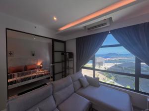 ein Wohnzimmer mit einem Sofa und einem großen Fenster in der Unterkunft Jesselton Quay Suite by Backyard in Kota Kinabalu