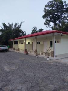 un edificio con techo rojo y aparcamiento en Margereth Cottage, en Kuala Penyu