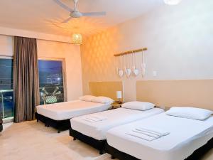 a room with three beds and a window at Awa De Mar Hotel in Tolú