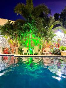 una piscina con sillas y palmeras por la noche en Awa De Mar Hotel, en Tolú