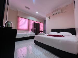- 2 lits dans une chambre avec des lumières roses dans l'établissement HOTEL RAUDHAH Kerteh, à Kerteh