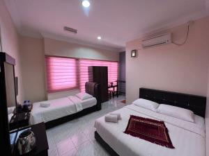 a hotel room with two beds and a table at HOTEL RAUDHAH Kerteh in Kertih