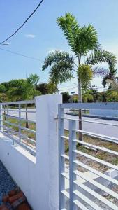 a white fence with a palm tree behind it at The Second Homestay in Port Dickson