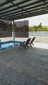 zwei Bänke unter einem Pavillon neben einem Pool in der Unterkunft The Second Homestay in Port Dickson