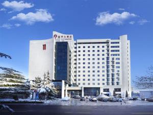 ein großes weißes Gebäude mit auf einem Parkplatz geparkten Autos in der Unterkunft 潍坊富华大酒店B座 The Farrington Hotel B in Weifang