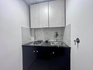 a small kitchen with a sink and white cabinets at Ayenda Edificio SantaMarta Medellín in Medellín