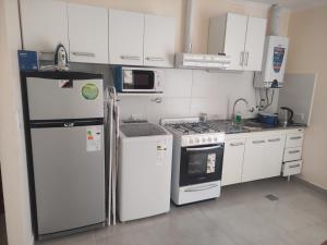 uma cozinha com electrodomésticos brancos e armários brancos em Belgrano 658 Nqn - Piso 1 Dto 2 em Neuquén