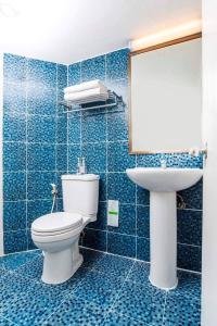 een blauw betegelde badkamer met een toilet en een wastafel bij Synsiri Ladprao 130 in Ban Bang Toei (1)