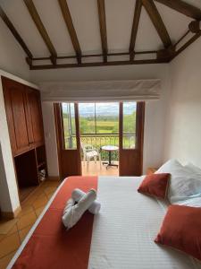 a bedroom with a large white bed with a view at Hostal Villa Anita in Villa de Leyva