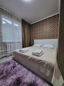 Кольсайские озера, гостиница Айару في Kurmenty: غرفة نوم مع سرير كبير مع سجادة أرجوانية